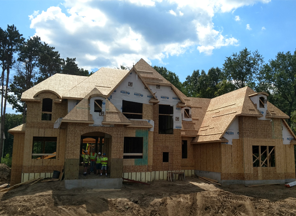 Home exterior being built, team members standing in entry way